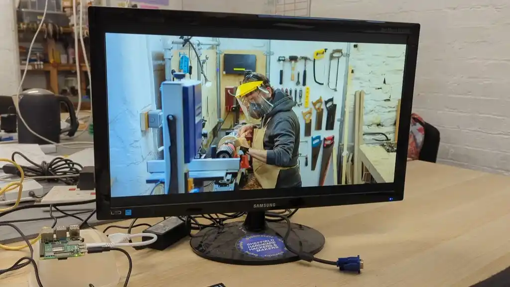 picture of TV screen, showing a picture of someone using a lathe